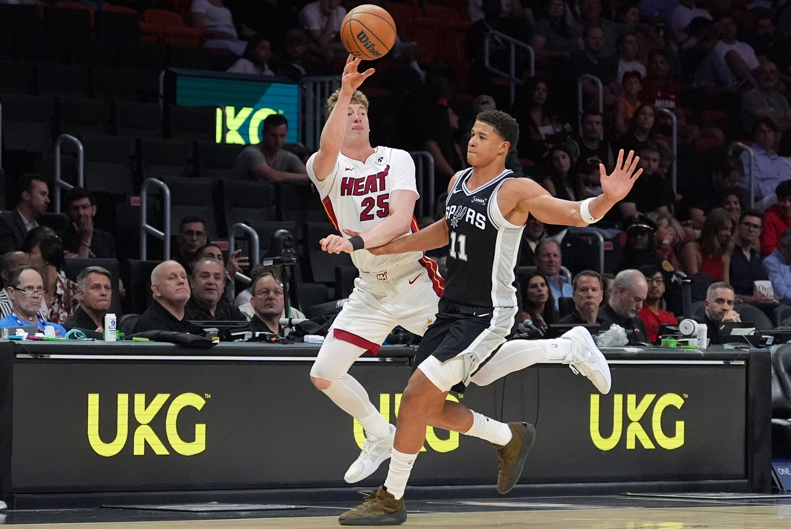 Miami Heat guard Kasparas Jakucionis (25) passes under pressure from San Antonio Spurs forward Carter Bryant (11) during the first half of a preseason NBA basketball game, Wednesday, Oct. 8, 2025, in Miami. (AP Photo/Rebecca Blackwell)