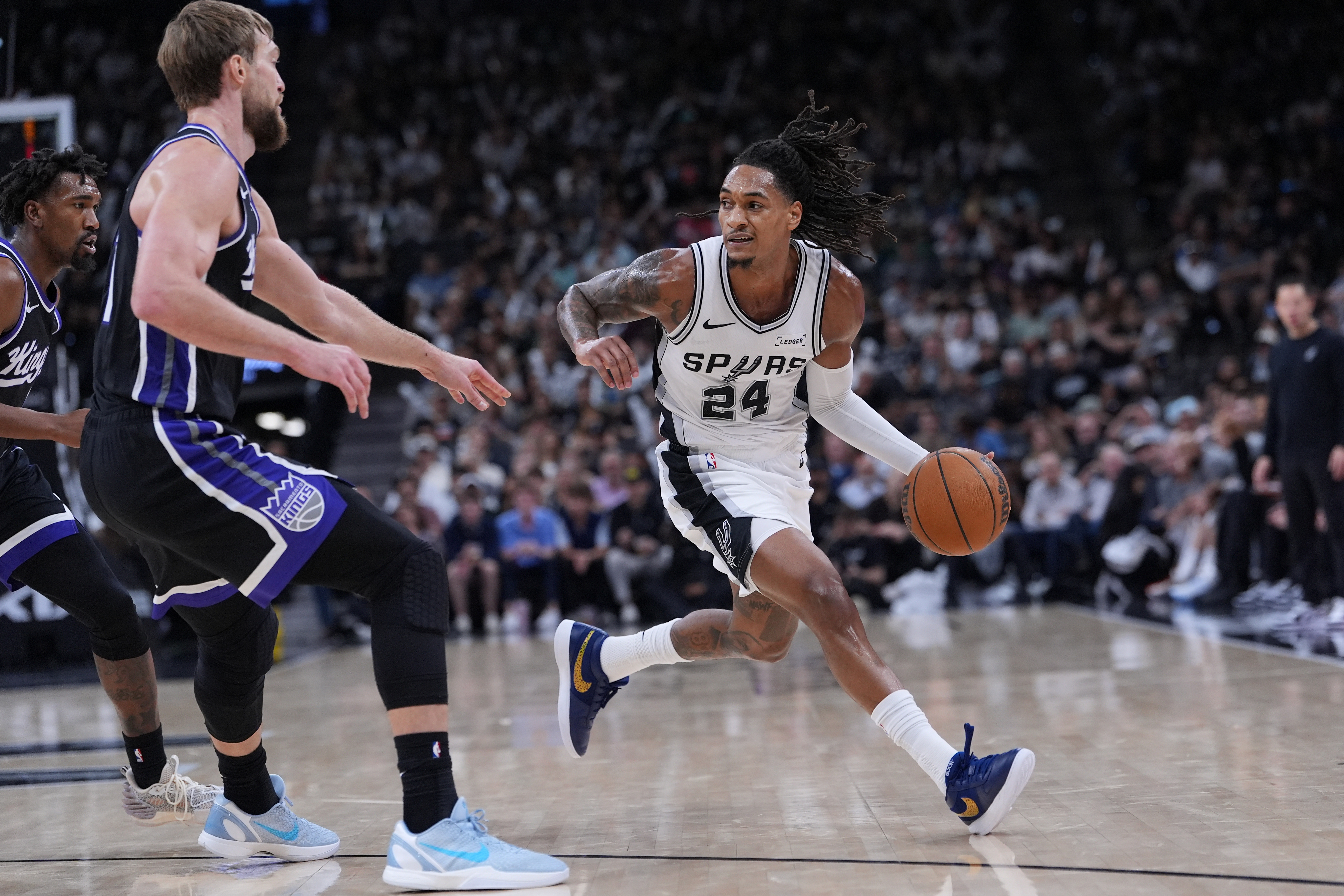 San Antonio Spurs guard Devin Vassell (24) drives around Sacramento Kings forward Domantas Sabonis (11) during the second half of an NBA basketball game in San Antonio, Sunday, Nov. 16, 2025. (AP Photo/Eric Gay)