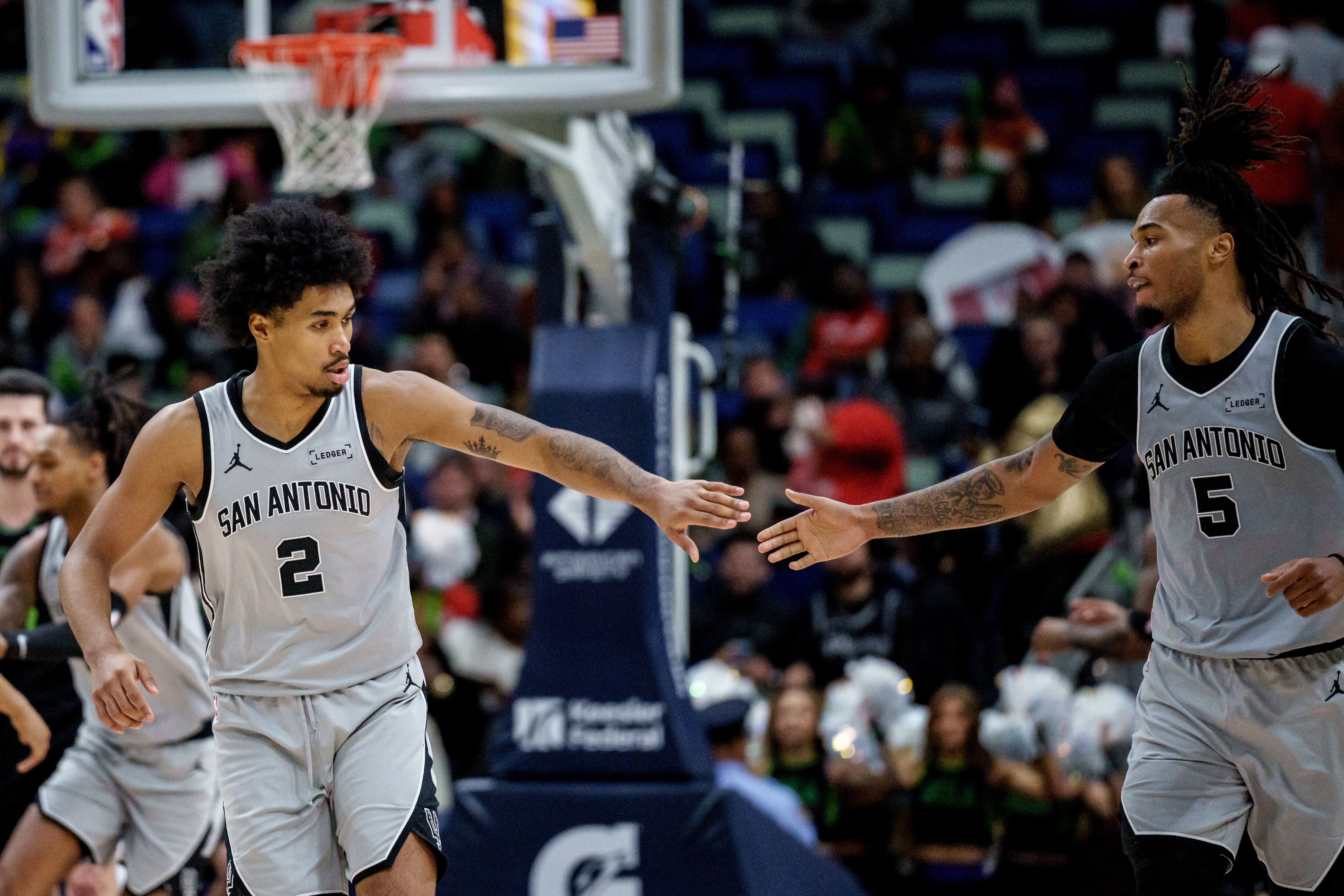 San Antonio Spurs guard Dylan Harper (2) celebrates with San Antonio Spurs guard De'Aaron Fox (4) during the first half of an NBA basketball game against the New Orleans Pelicans in New Orleans, Monday, Dec. 8, 2025. (AP Photo/Matthew Hinton)