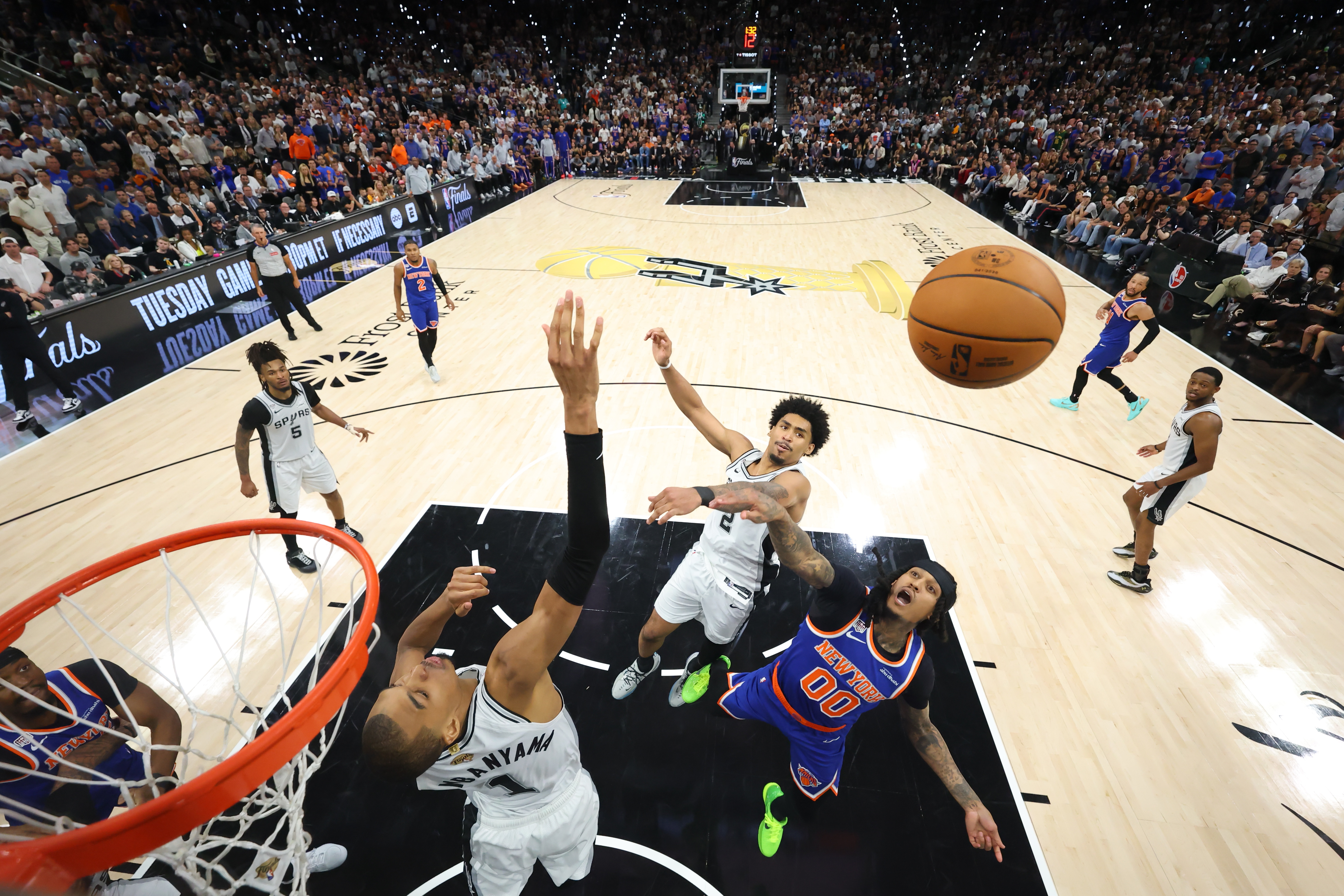 San Antonio Spurs forward Victor Wembanyama (1) and guard Dylan Harper (2) and New York Knicks guard Jordan Clarkson (00) battle for the rebound during the first half of Game 5 of the NBA Finals basketball series, Saturday, June 13, 2026, in San Antonio. (Geoff Burke/Pool Photo via AP)