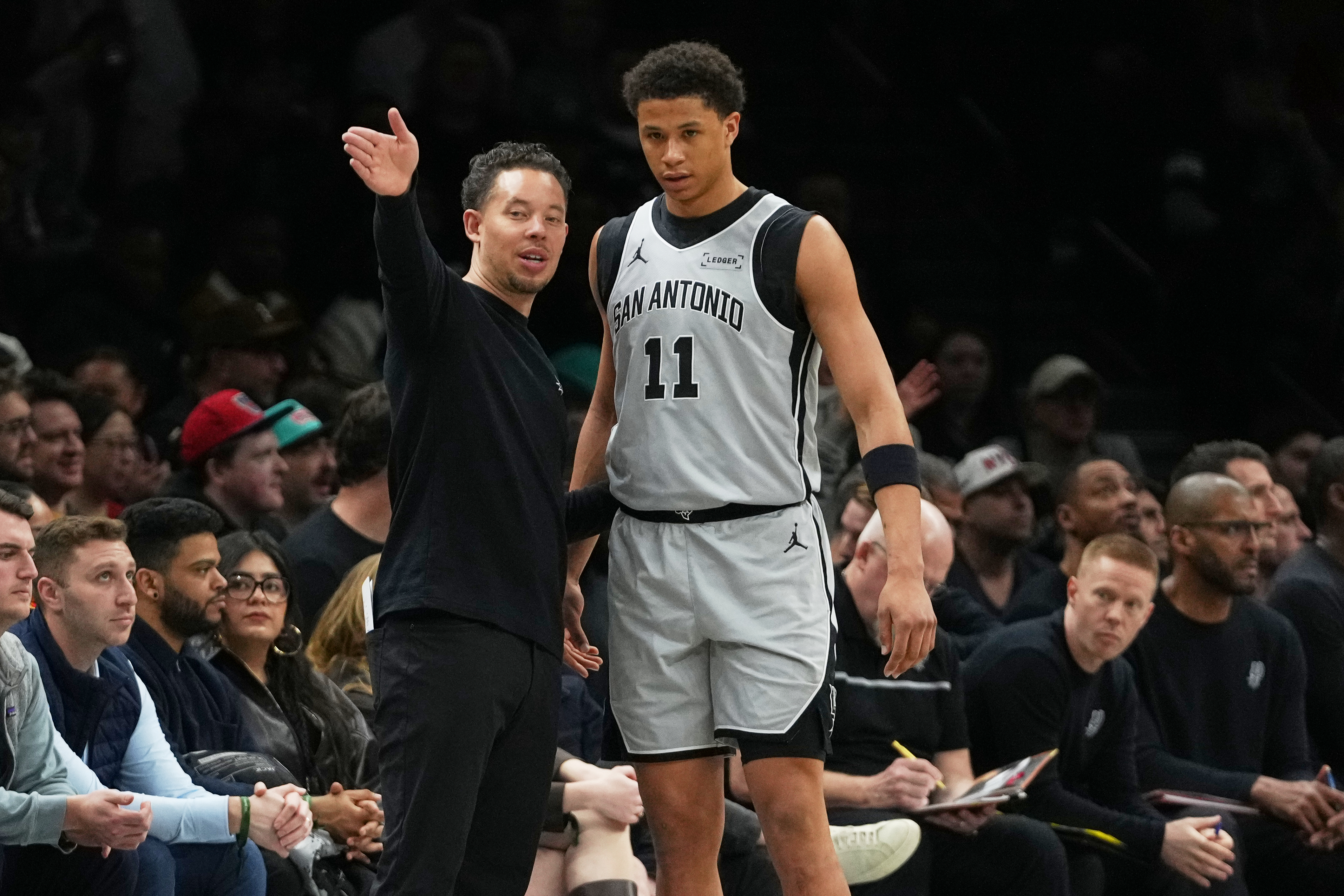 San Antonio Spurs Head Coach Mitch Johnson, left, talks to Carter Bryant (11) during the first half of an NBA basketball game against the Brooklyn Nets Thursday, Feb. 26, 2026, in New York. (AP Photo/Frank Franklin II)