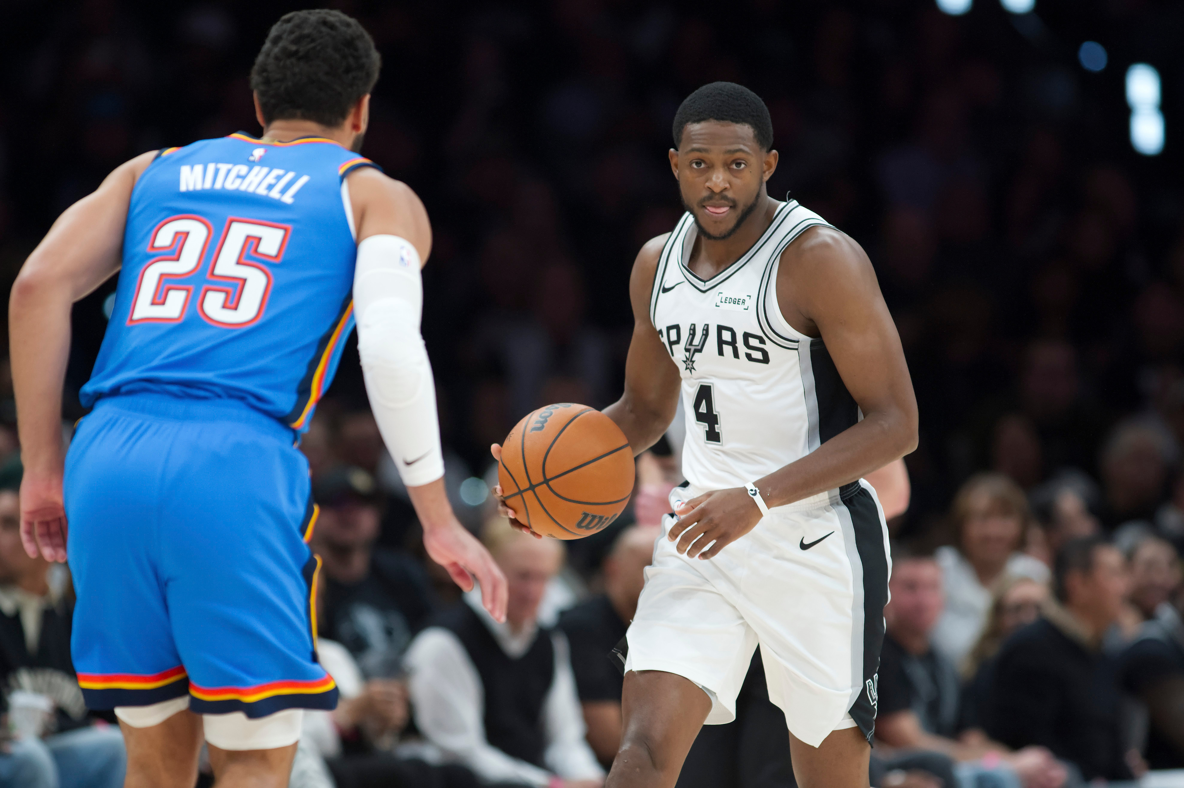 San Antonio Spurs guard De'Aaron Fox (4) drives against Oklahoma City Thunder guard Ajay Mitchell during the first half of an NBA basketball game, Tuesday, Oct. 20, 2026, in San Antonio. (AP Photo/Darren Abate)